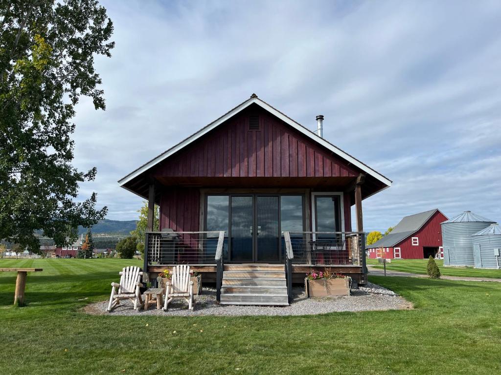 a small red building with chairs and a porch at New Cabin with Spectacular Views of Flathead Lake. in Somers