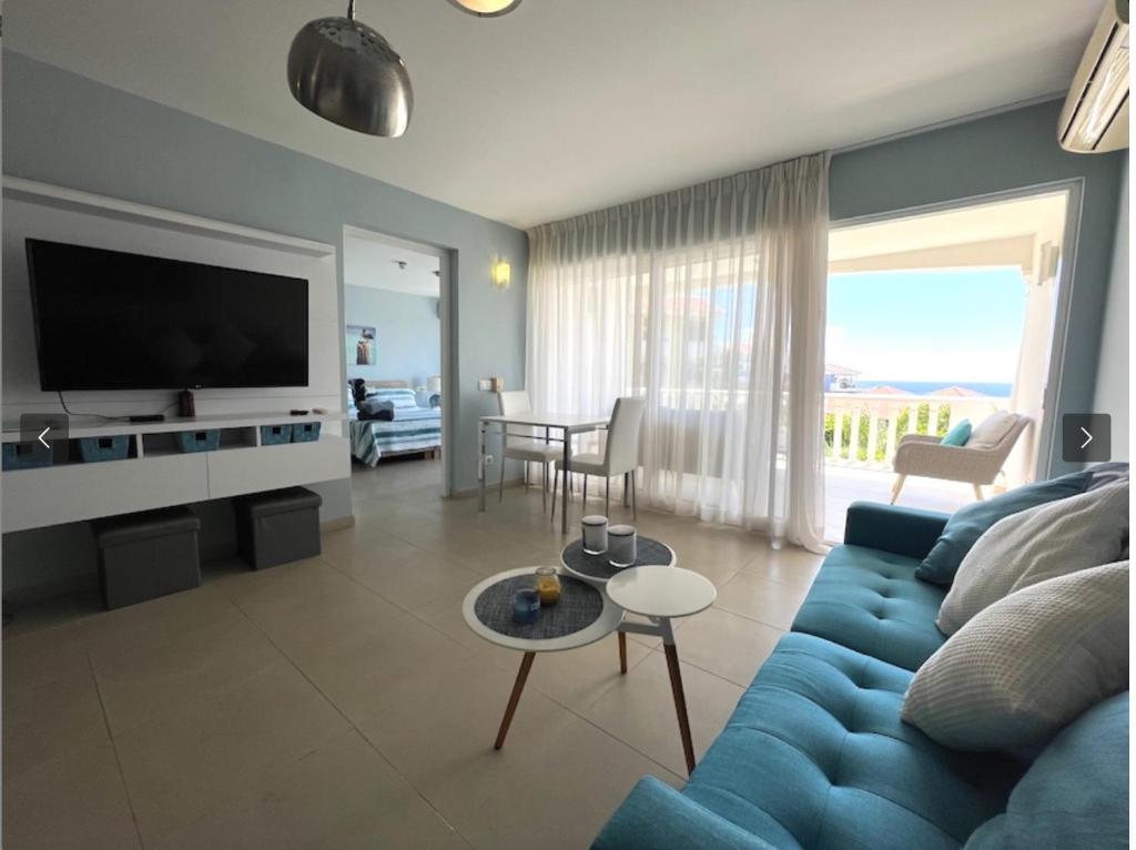 ein Wohnzimmer mit einem blauen Sofa und einem TV in der Unterkunft UntoldCondo in Blue Bay