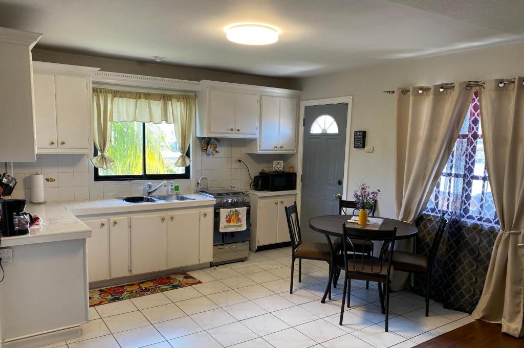 a kitchen with white cabinets and a table and a sink at 1 Bedroom Apartment, in Coconut Drive San Fernando in San Fernando