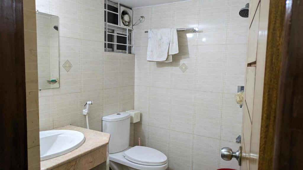 a bathroom with a white toilet and a sink at Sheikh Manama Tower in Dhaka