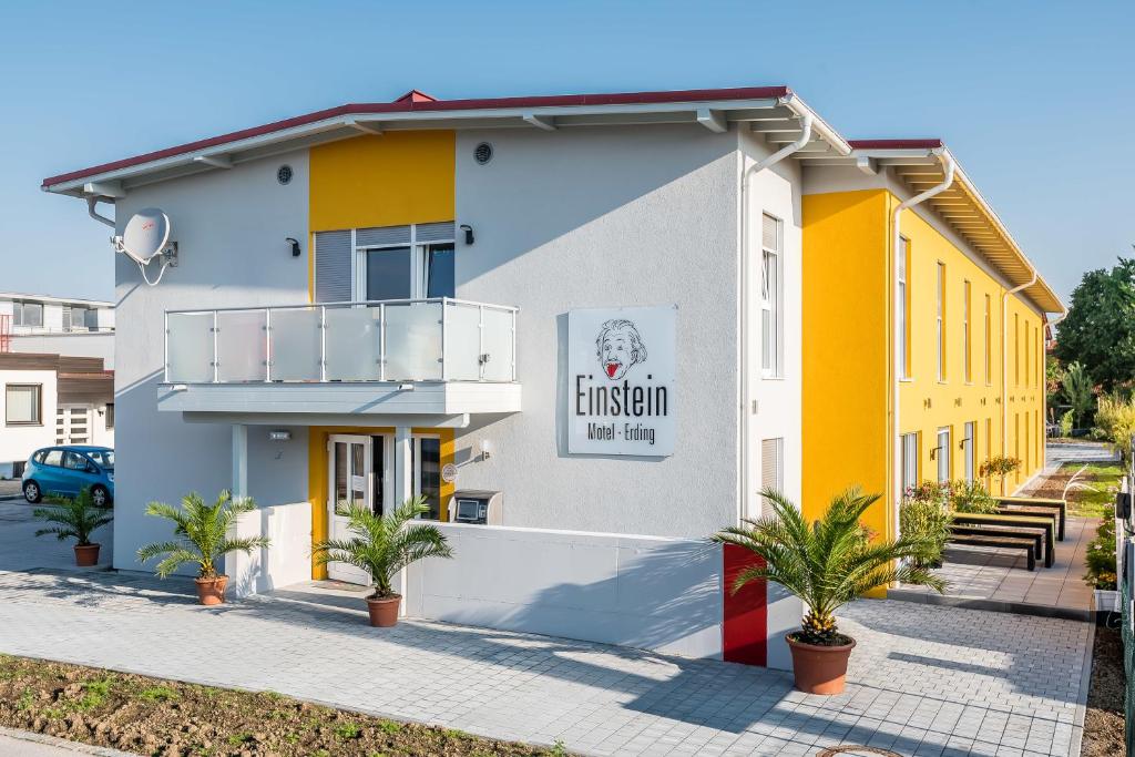 a white and yellow building with palm trees in front at FairSleep Motel Einstein Erding in Erding