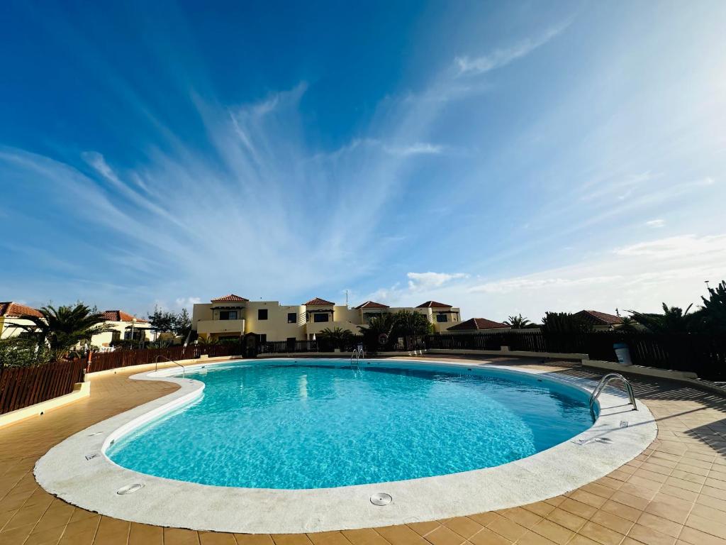 a large swimming pool in a yard with houses at Casa La Pepita in Caleta De Fuste