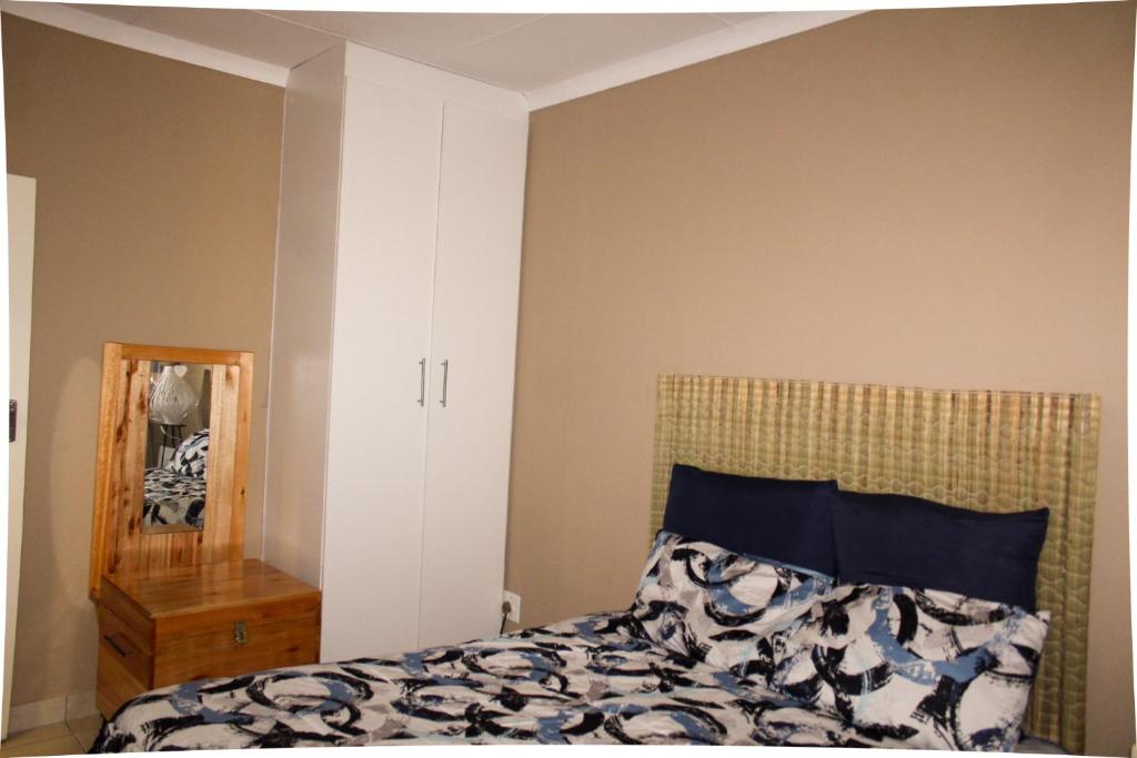 a bedroom with a bed and a mirror at City Centre Apartment in Mbabane