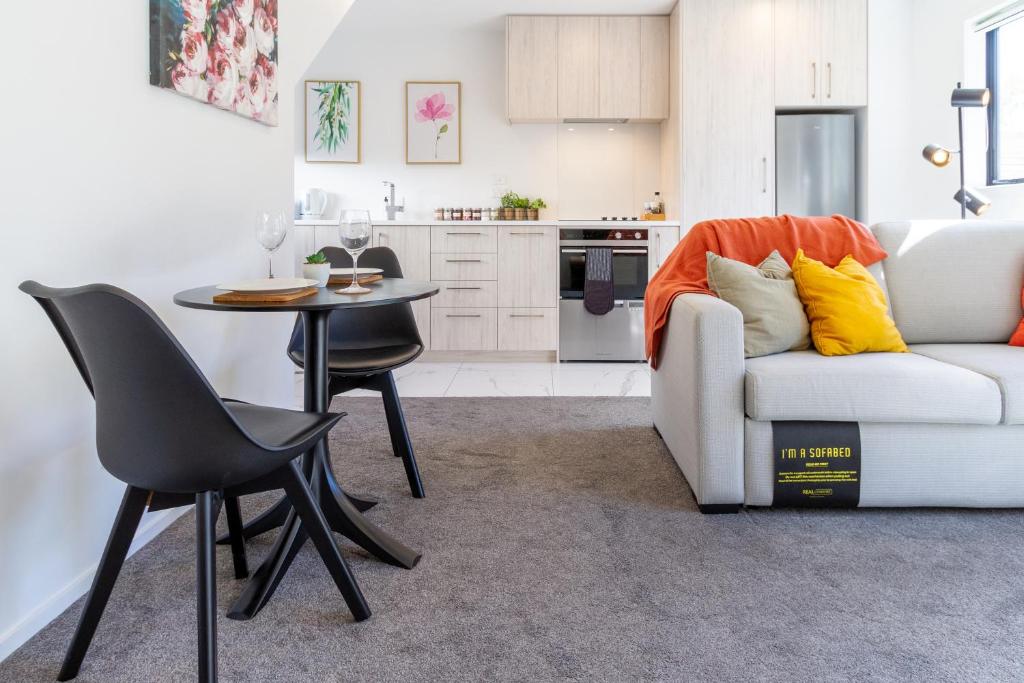 ein Wohnzimmer mit einem weißen Sofa und einem Tisch in der Unterkunft 1 Bedroom Gem with Hagley Park at your doorstep in Christchurch