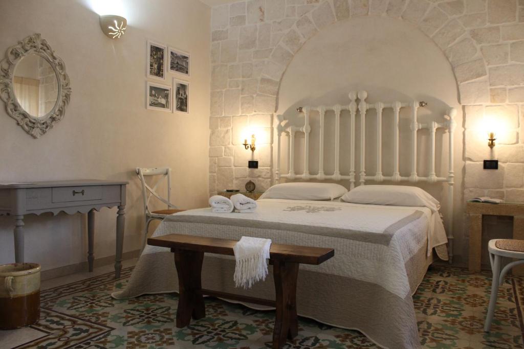 una camera con letto, tavolo e specchio di Masseria Tolla a Ostuni