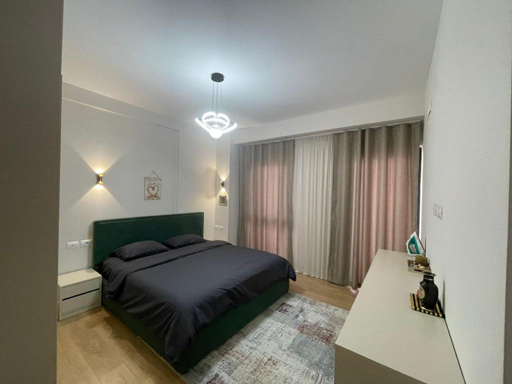 een slaapkamer met een groen bed en een tafel bij Garden Building Luxury Apartment in Tirana