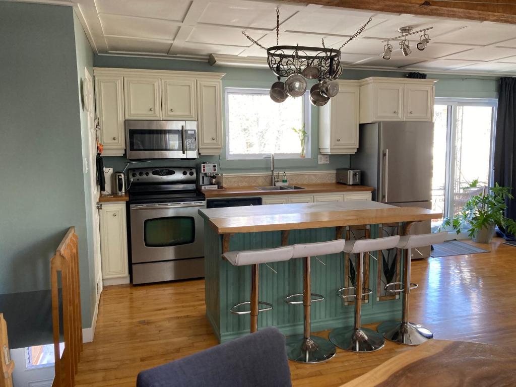 a kitchen with white cabinets and a green island in it at Owl House - Hot Tub with rooftop terrasse in Quebec City