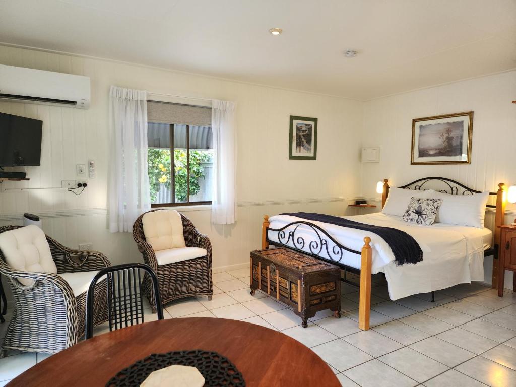 a bedroom with a bed and a chair and a table at Chillagoe Cabins and Tours in Chillagoe