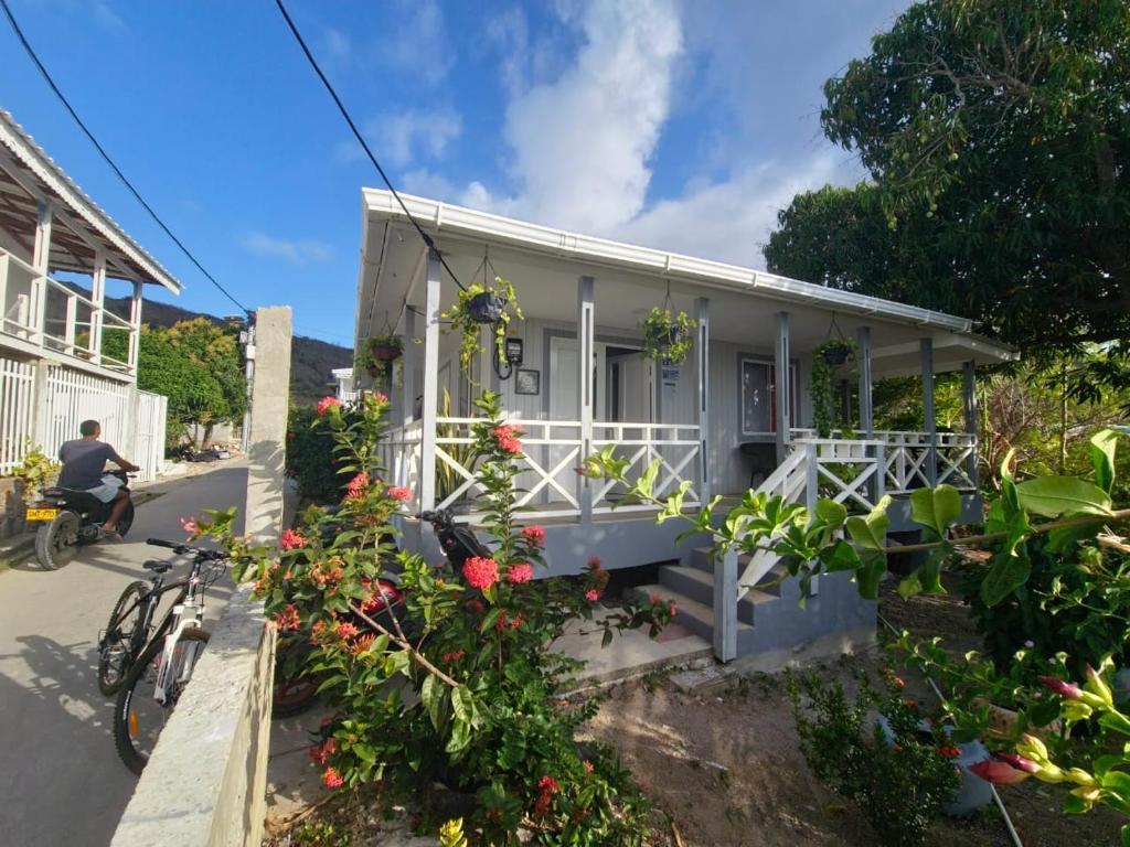 a small white house with flowers and a man on a bike at Posada Hill View in Providencia