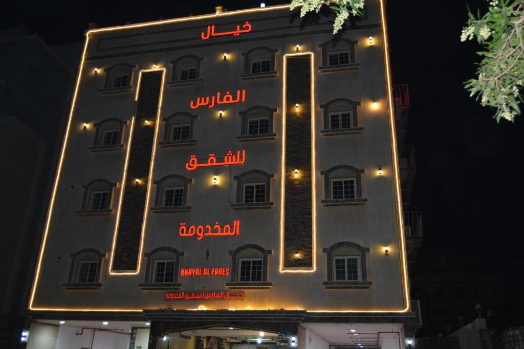 a sign for a hotel with lights on it at خيال الفارس للشقق المخدومة in Quwayzah