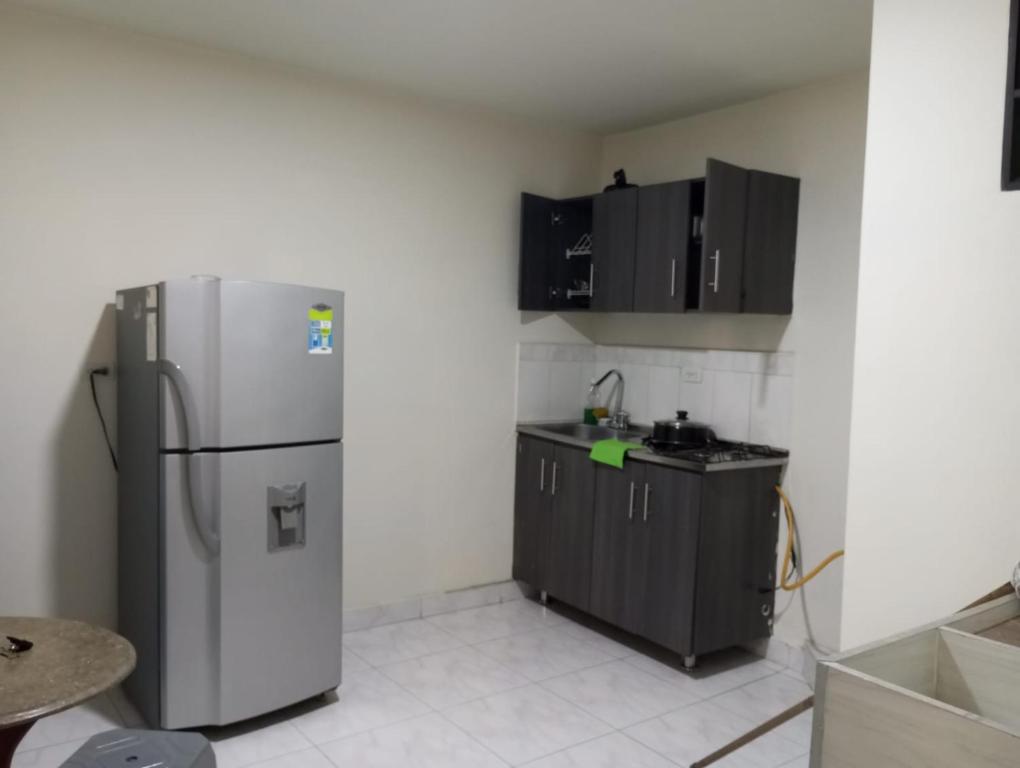 d'une cuisine équipée d'un réfrigérateur en acier inoxydable et de placards noirs. dans l'établissement Aparta-estudio amoblado en Medellin, Campo Valdes, à Medellín