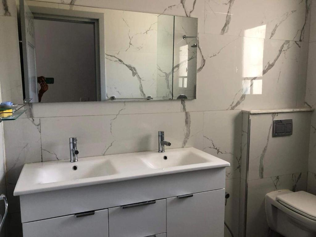 a bathroom with a white sink and a mirror at La villa H in Houmt Souk