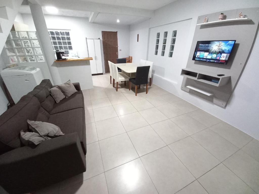 ein Wohnzimmer mit einer Couch und einem Tisch mit einem Fernseher in der Unterkunft Casa de Praia - Frente para o MAR in Xangri-lá