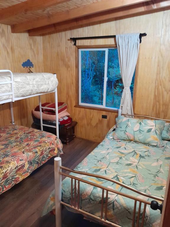 a bedroom with two bunk beds and a window at Cabaña Cacique Vista Hermosa in Cochamó