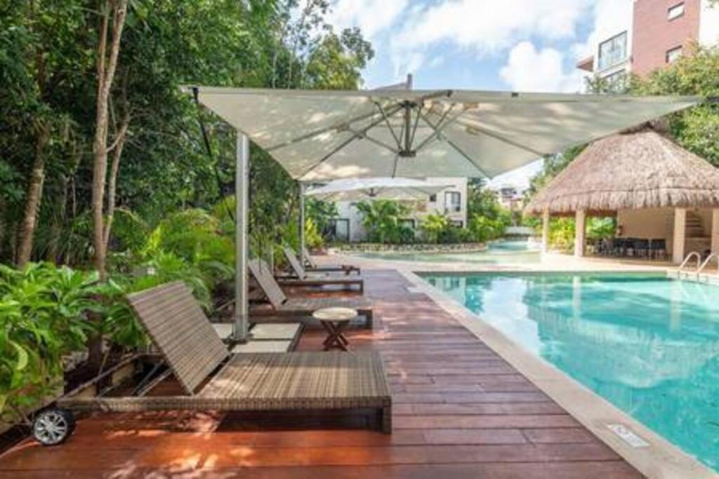 - une piscine avec des chaises et un parasol à côté de la piscine dans l'établissement Paraíso en Lagunas de Mayakoba, à Playa del Carmen