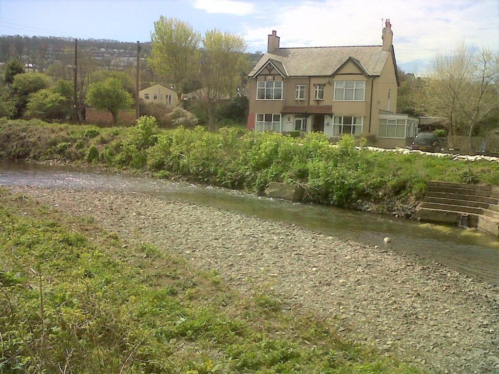a house with a river in front of a house at Beach House, Llanddulas near Colwyn Bay in Llanddulas