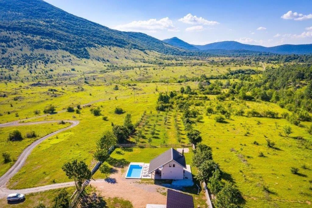 an aerial view of a house in a field with a pool at Family friendly house with a swimming pool Rudopolje Bruvanjsko, Zagora - 21427 in Gračac