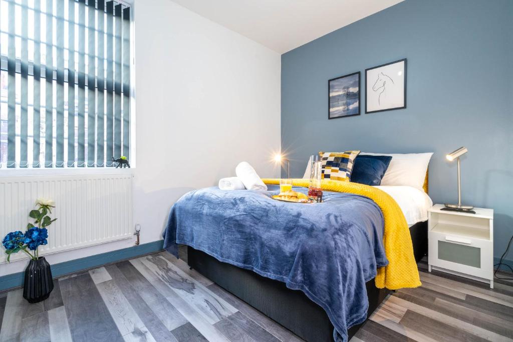 a bedroom with blue walls and a bed with a yellow blanket at Sky rooms modern studio apartment 2 in Birmingham