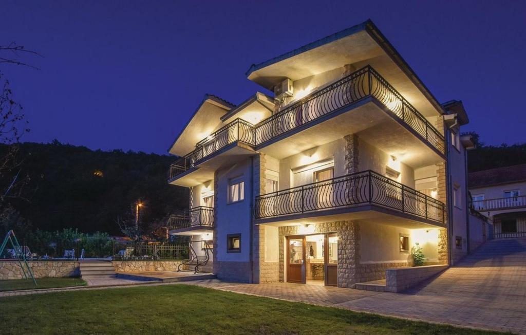 Un grand bâtiment blanc avec balcon est disponible la nuit. dans l'établissement Family friendly house with a swimming pool Grab, Zagora - 22830, à Trilj