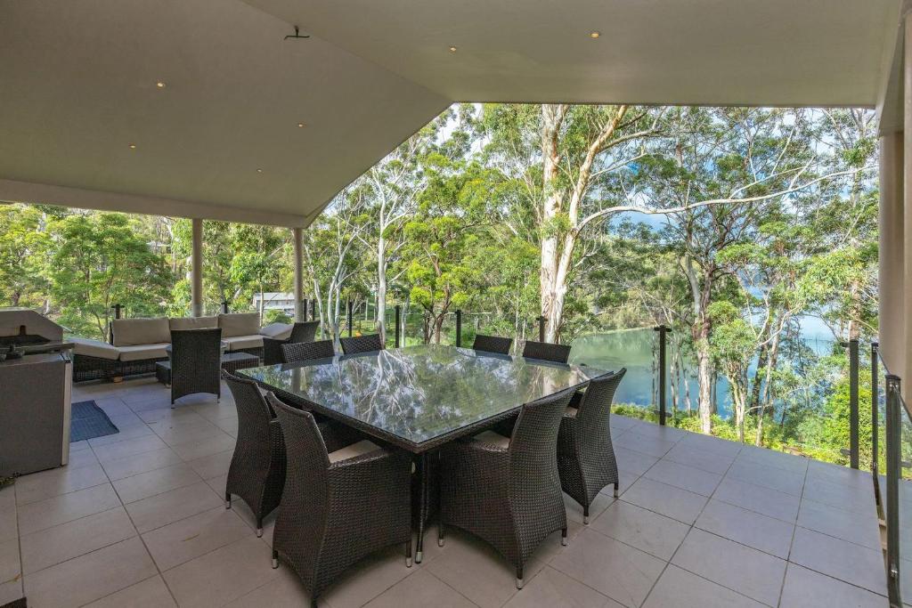 a dining room with a glass table and chairs at A Yarraangunthi in Smiths Lake