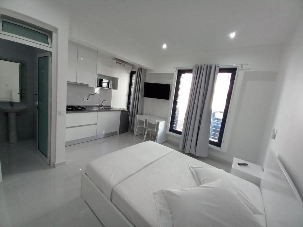 a white bedroom with a bed and a kitchen at Apto T0 na Capital in Praia