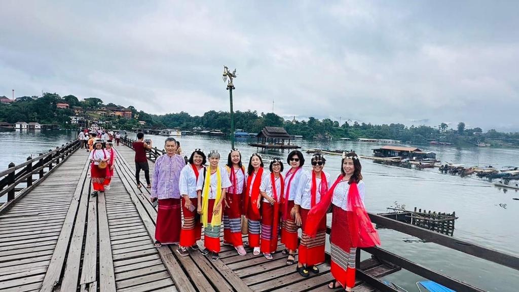 un gruppo di persone che si trovano su un ponte di legno di Baan Dongsak River view a Sangkhla Buri