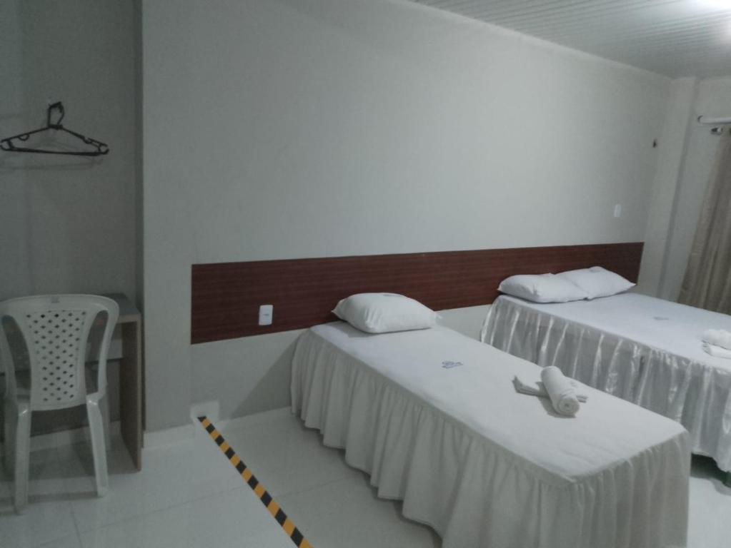 a room with two beds and a table and a chair at HOTEL NOVAES in Castanhal