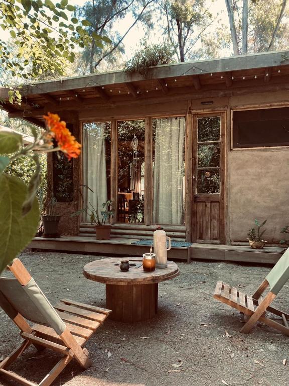 eine Terrasse mit einem Tisch und Stühlen sowie ein Haus in der Unterkunft Eco cabaña Tierra Fértil in Santa Ana