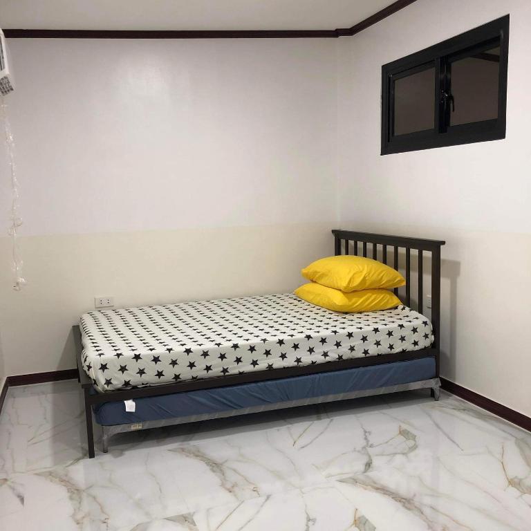 uma cama com almofadas amarelas num quarto em Jirah’s inn em Legazpi