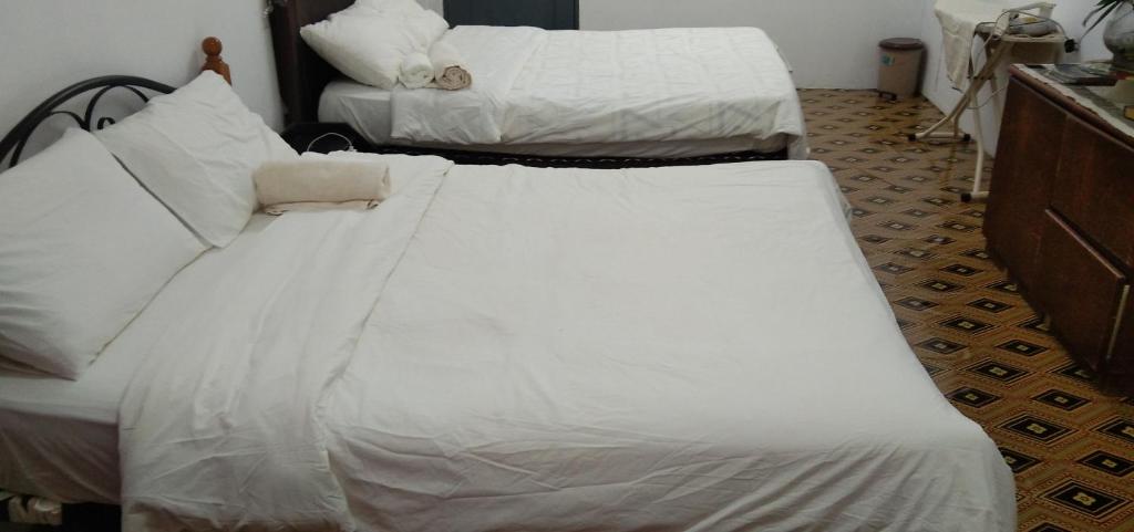 una camera con due letti con lenzuola bianche di Melrose homestay and transport a Kampong Parit