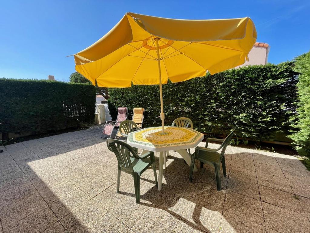 - une table avec un parasol jaune sur la terrasse dans l'établissement Maison Bretignolles-sur-Mer, 3 pièces, 6 personnes - FR-1-231-238, à Bretignolles-sur-Mer