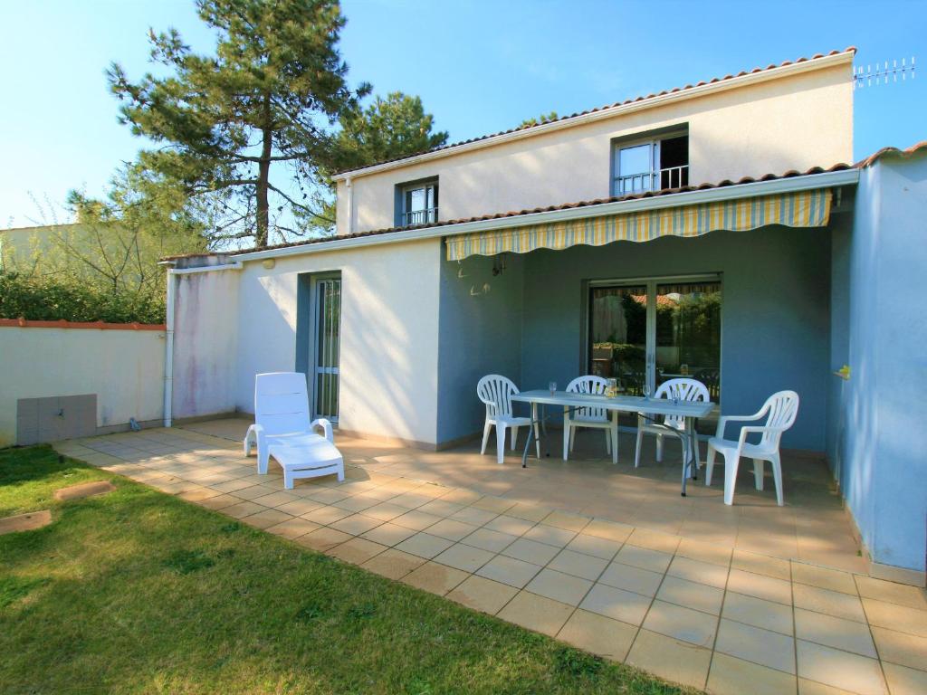 une terrasse avec une table et des chaises ainsi qu'une maison dans l'établissement Maison avec Jardin près de la Plage, WiFi, 300m du Phare - FR-1-22-291, à La Tranche-sur-Mer