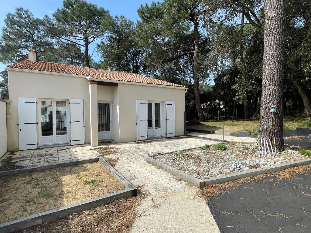une petite maison blanche avec un arbre en face dans l'établissement Maison familiale au cœur des pins avec jardin, proche plage, animaux acceptés, 700m de la côte. - FR-1-22-363, à La Tranche-sur-Mer