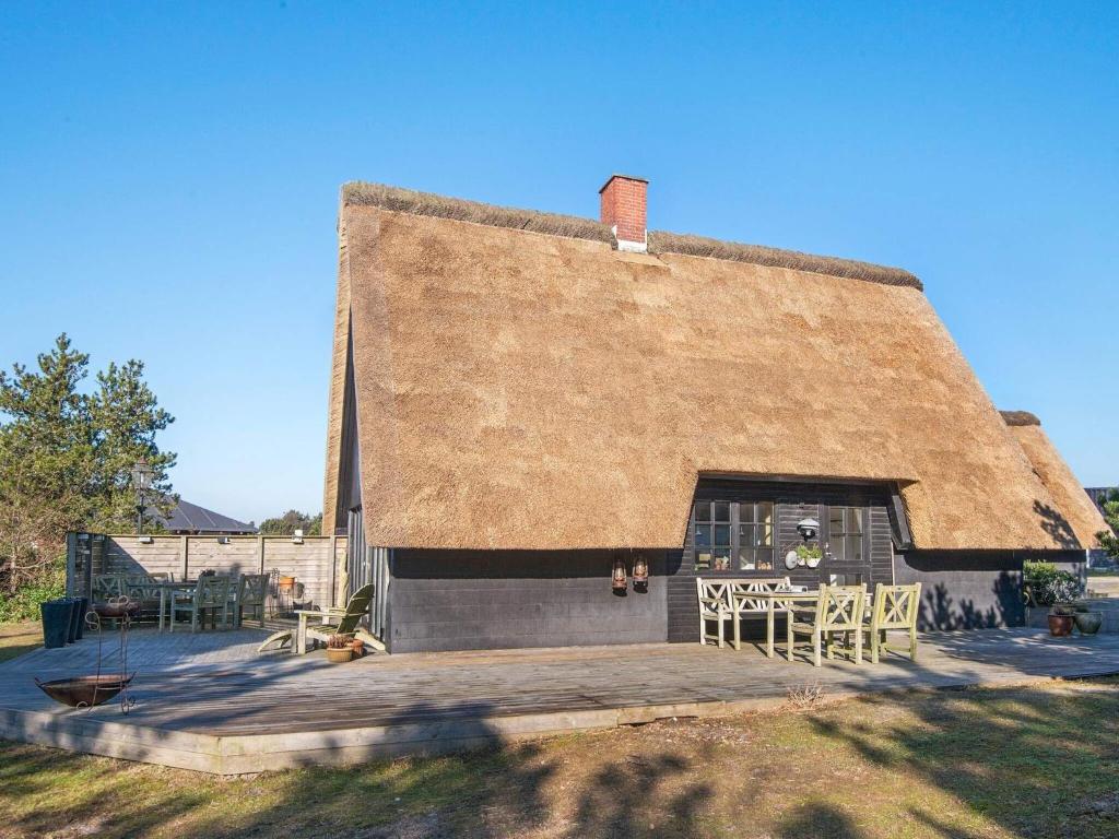 a building with a thatched roof with a table at Holiday home Fanø XX in Fanø