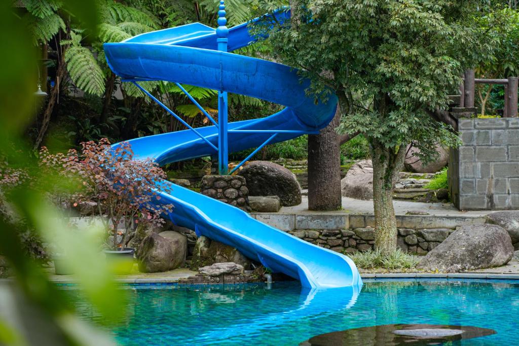 uno scivolo d'acqua blu nel centro di una piscina di Taman Wisata Bougenville a Malabar