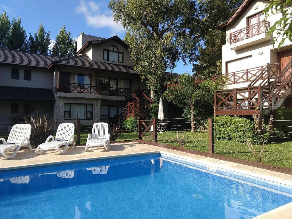 una piscina con 2 sillas y una casa en Maritimo Apart en Pinamar