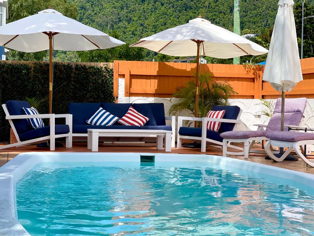 uma piscina com duas cadeiras e guarda-sóis em Paradise Court Holiday Units em Airlie Beach