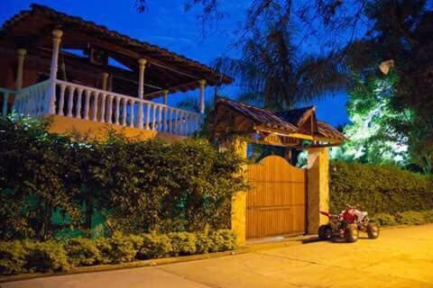a house with a motorcycle parked in front of a garage at Finca Villa Lili in Santa Fe de Antioquia