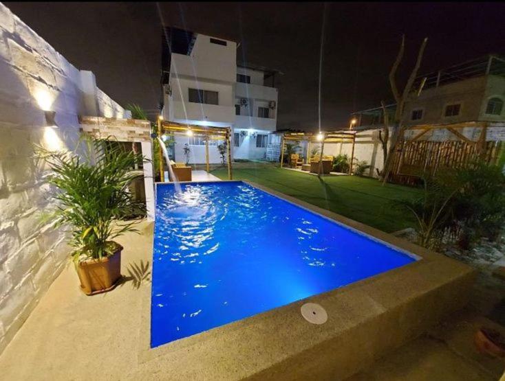 a large blue swimming pool in a yard at night at Mare S&M Casa Hostal in Manta
