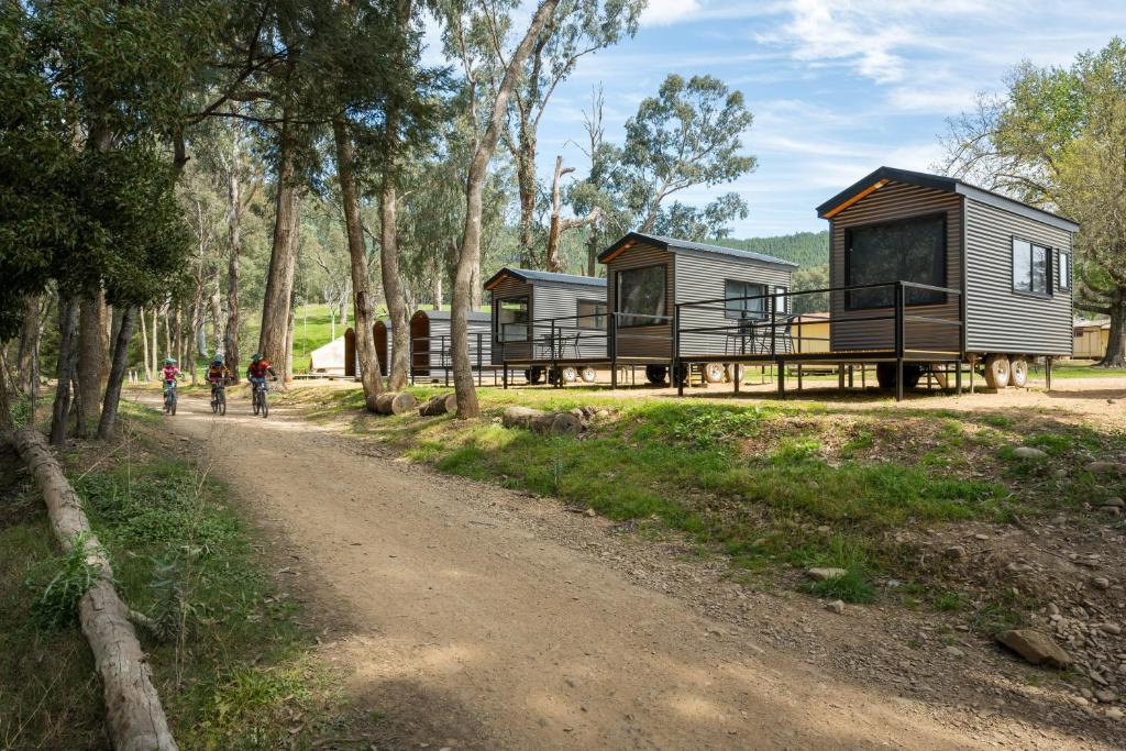 a couple of people walking down a dirt road next to a cabin at Bright Cabin Park in Bright