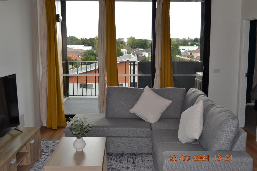 a living room with a couch and a large window at ZMITH Apartment - BROOKE Canberra in Belconnen