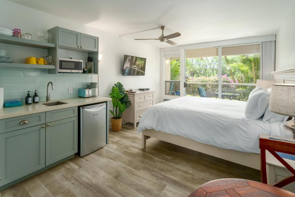 a bedroom with a bed and a kitchen with a window at Walkable to Beach, Restaurants & Shops. Remodeled! in Wailea