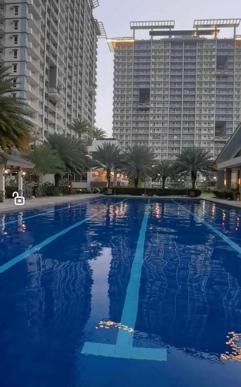 una gran piscina azul con altos edificios en el fondo en Modern 2BR Condo with Fiber Net, en Davao City