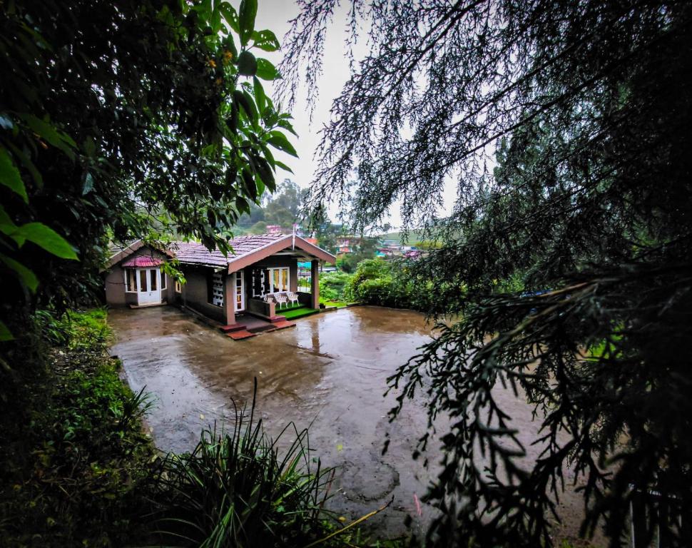 um rio com dois pequenos edifícios no meio em Wood House 1 em Ooty