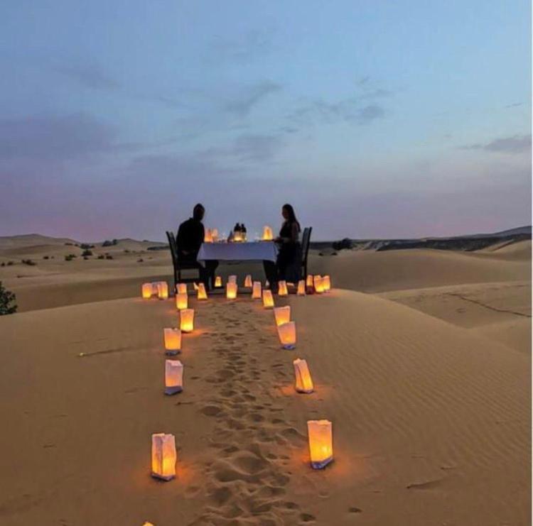 een groep mensen aan een tafel in de woestijn bij Bivouac Karim Sahara in Zagora