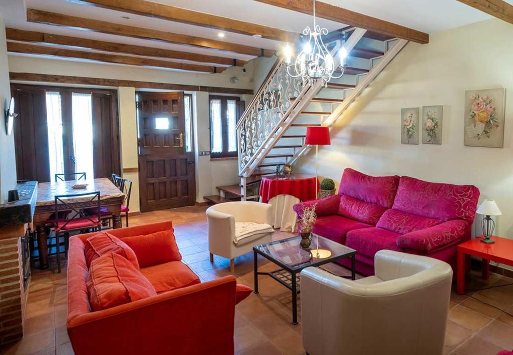 a living room with red furniture and a staircase at EL ALMENDRO in Aldeadávila de la Ribera