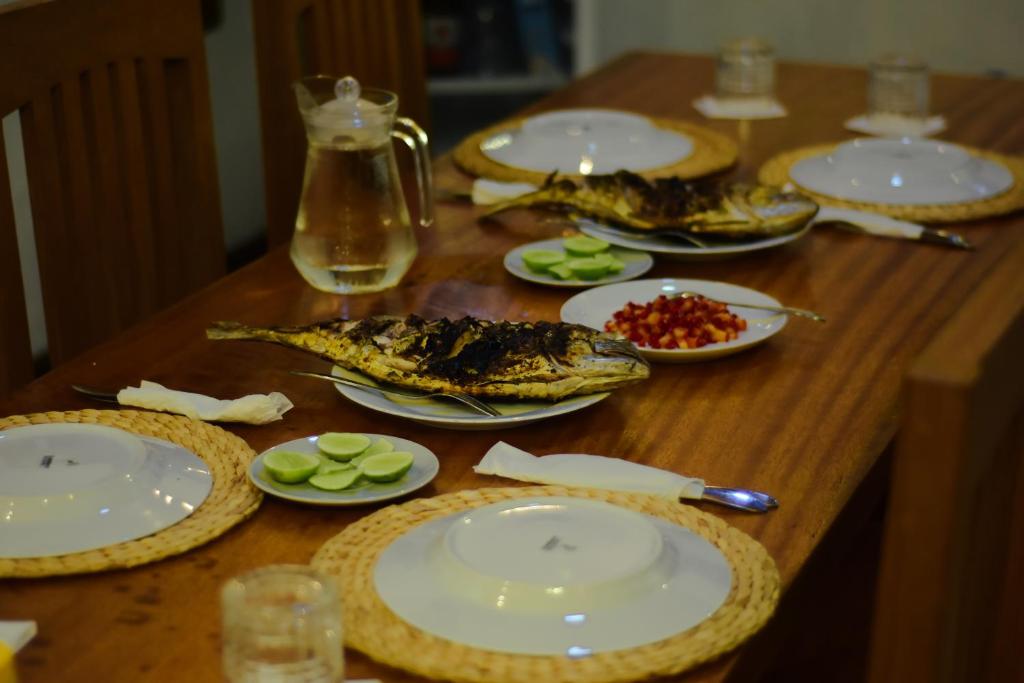 a wooden table with plates of food on it at Suzi Beach House in Tua Pejat