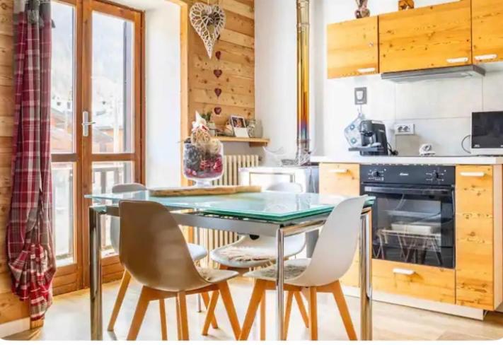 a kitchen with a glass table and white chairs at Il Baitino Innamorato in Pragelato