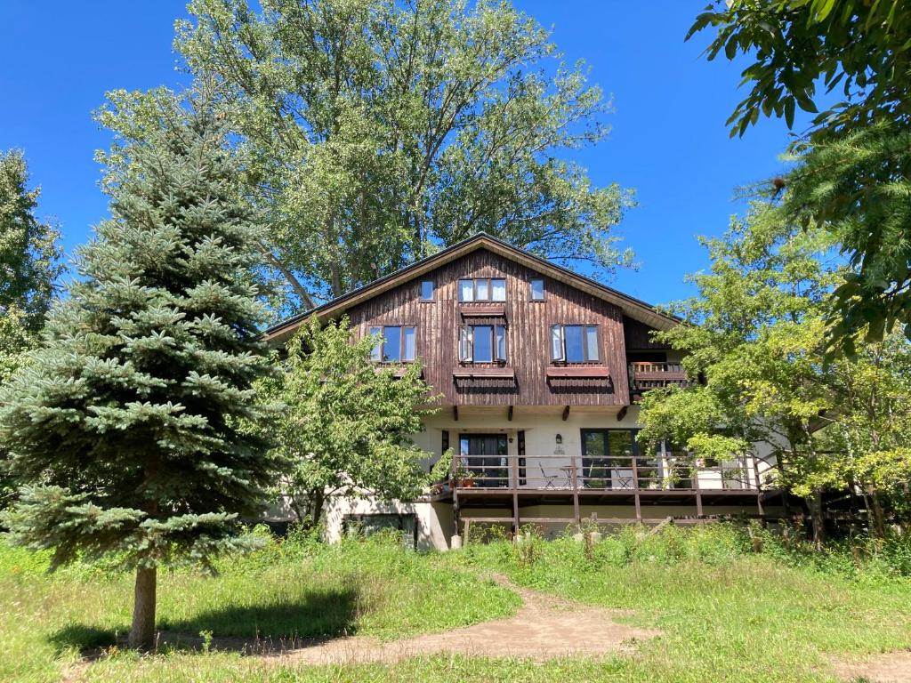 ein Holzhaus mit einem Baum davor in der Unterkunft Pension Raclette in Nakafurano