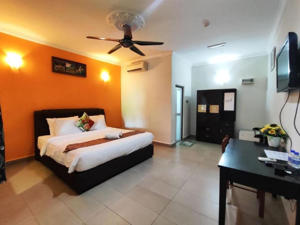 a bedroom with a bed with an orange wall at Sweet Cenang Memories Inn in Pantai Cenang